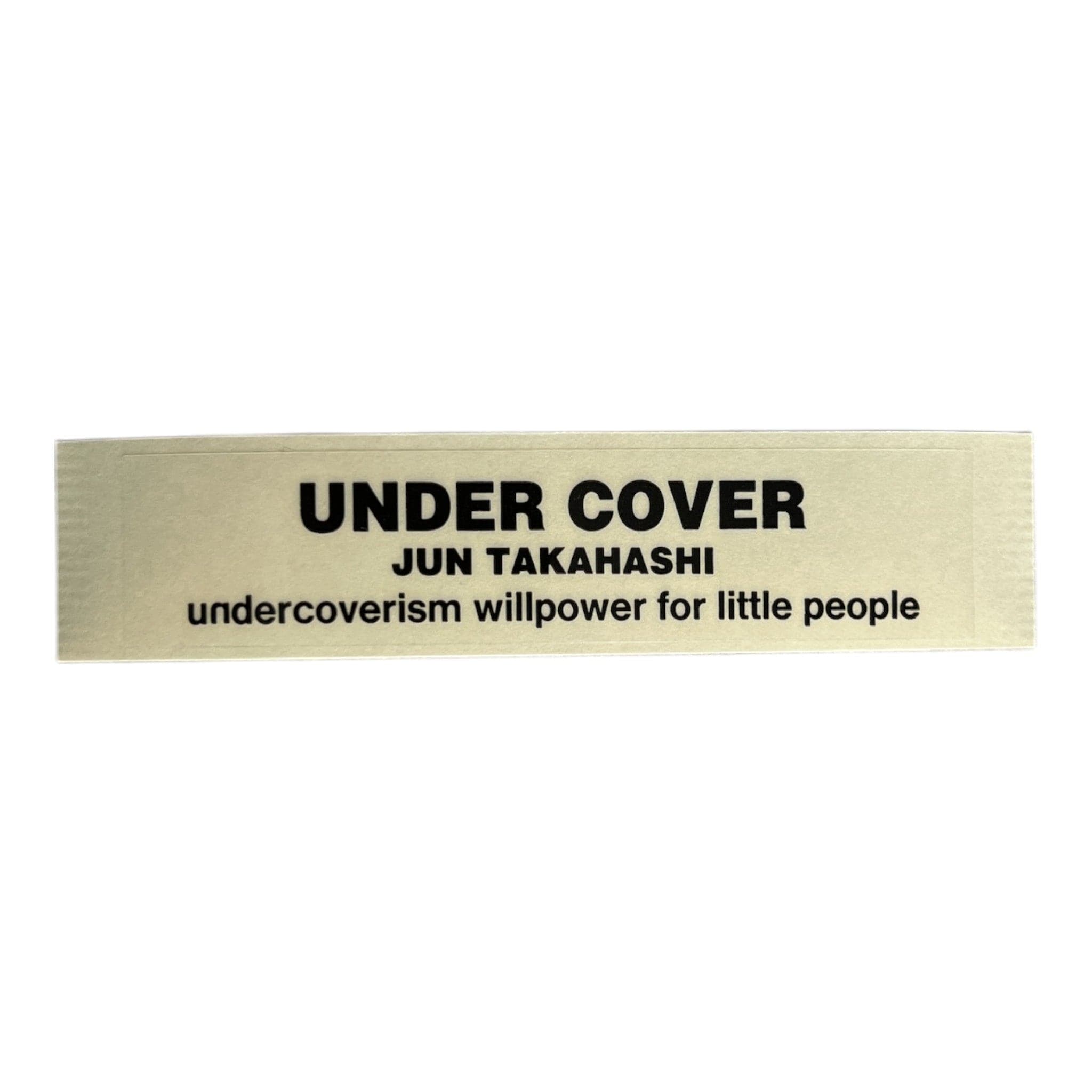 Text label with 'Under Cover' and 'Jun Takahashi' on a beige background